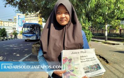 Anisa Rahmawati membawa koran Jawa Pos dijajakan di simpang tiga Panggung, Jebres, kemarin (11/6).