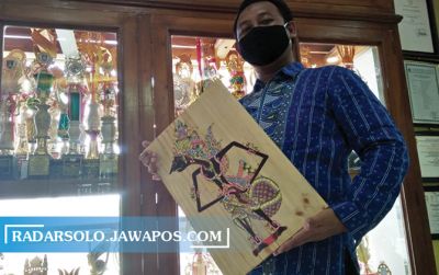 Agung Sudarwanto memegang ukiran wayang dari kayu jati bekas.