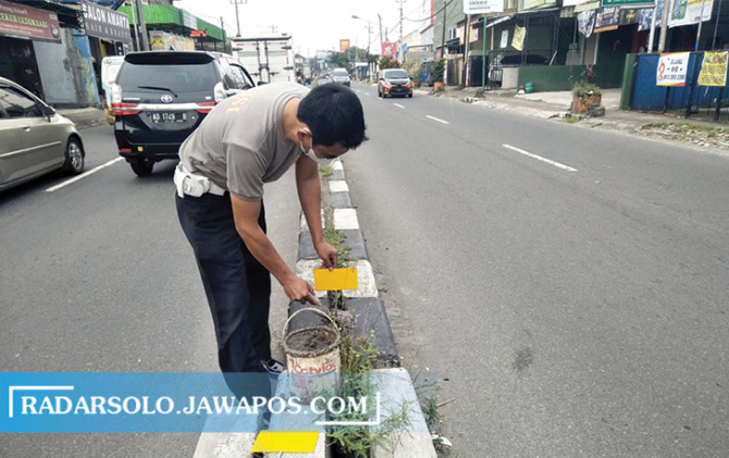 TEKAN LAKALANTAS: Anggota Satlantas Polres Sukoharjo memasang scootlight di jalan Pasar Telukan-Sanggar Wayang, Sukoharjo, Minggu (27/3). (IWAN KAWUL/RADAR SOLO)