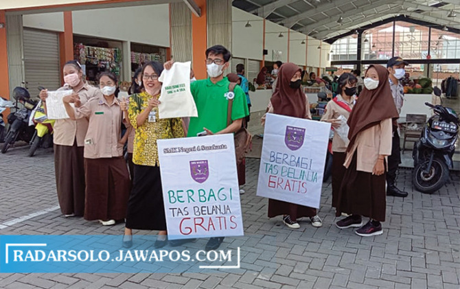 KURANGI PLASTIK: Siswa SMKN 4 Surakarta membagikan tas ramah lingkungan di Pasar Senggol Purwosari, Jumat (22/4). (GERSON/RADAR SOLO)