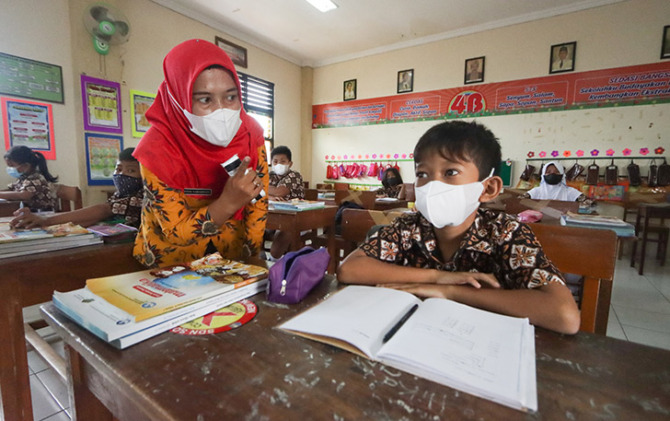 RANGKAP TUGAS: Guru mendampingi siswanya dalam pembelajaran tatap muka (PTM) di salah satu SD negeri di Kota Solo, belum lama ini. Disdik sedang mencari formulasi atasi krisis guru. (M. IHSAN/RADAR SOLO)