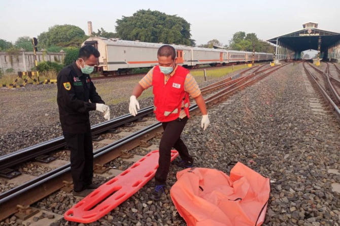 Petugas tengah mengevakuasi jenazah yang diduga menabrakan diri  ke kereta api yang tengah melintas. (AHMAD KHAIRUDIN/RADAR SOLO)