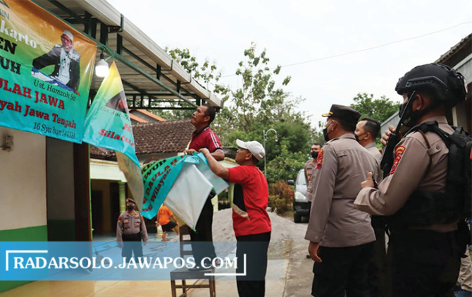 LANGKAH CEPAT: Tim Kepolisian dari Polres Sukoharjo melakukan penurunan papan nama dan spanduk bertuliskan Khilafatul Muslimin di sekretariat Khilafatul Muslimin yang berada di berada di Dukuh Gondang RT 01 RW12 Desa Polokarto, Kecamatan Polokarto.  (IWAN