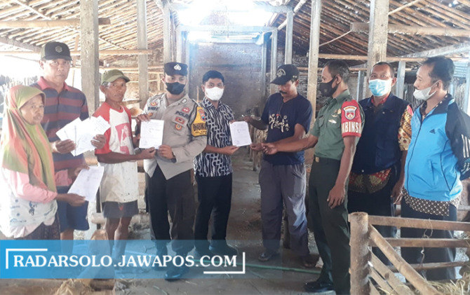 JEMPUT BOLA: Babinsa dan bhabinkamtibas serahkan surat sehat ke hewan yang akan dikurbankan. (AHMAD KHAIRUDIN/RADAR SOLO)