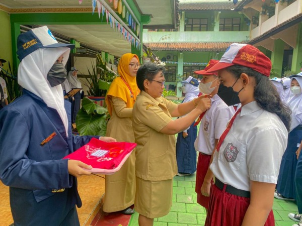 TELADAN: Kepala SMPN 1 Kartasura Viveri Wuryandari sematkan tanda kepada murid baru di sela kegiatan MPLS. (ISTIMEWA)