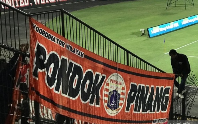 Suporter Persija Jakarta memanjat pagar pembatas untuk memasang spanduk tim saat jelang laga perdana Liga 1 Indonesia 2022/2023 antara Persija Jakarta versus Bali United FC di Stadion Kapten I Wayan Dipta, Gianyar, Bali, Sabtu (23/7). (ANTARA)
