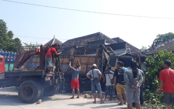 Proses evakuasi truk tronton yang terjebak di teras rumah usai terlibat kecelakaan karambol di Jalan Pakis-Daleman Km 3, Desa Bentangan, Wonosari.