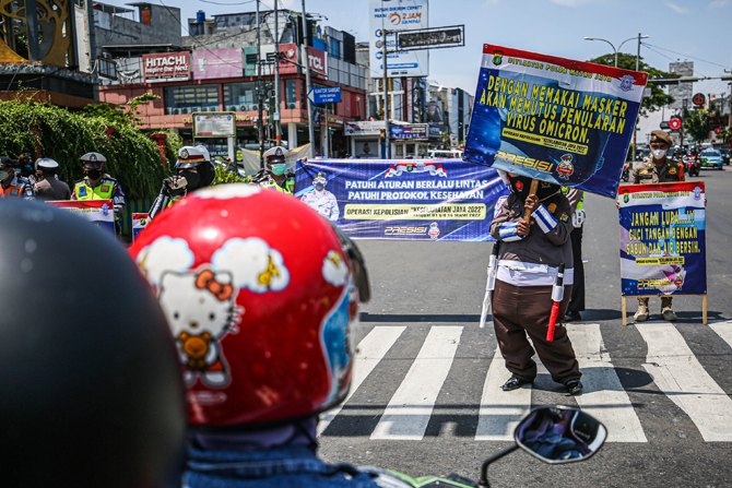 Petugas kepolisian bersama Dishub, Satpol PP Dan Komunitas Aku Badut Indonesia melakukan sosialisasi cegah penyebaran Virus Omicron di Jalan Margonda, Depok, Jawa Barat, Senin (14/3). (Miftahulhayat/Jawapos)