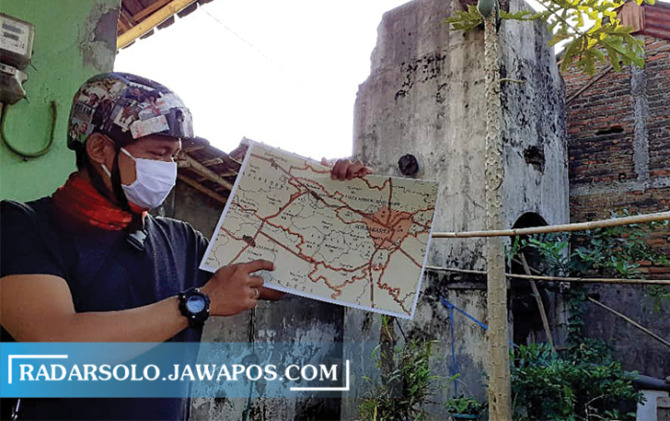 CINTA SEJARAH: Komunitas pemerhati sejarah Kecamatan Baki menunjukkan peta lokasi pabrik tembakau di dekat KUA Baki. Di belakangnya masih berdiri bekas bangunan tandon air. (IWAN KAWUL/RADAR SOLO)