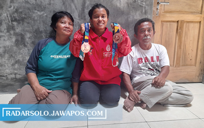 BANGGA: Yuni Widya Irianti bersama orang tuanya menunjukkan medali APG. (RUDI HARTONO/RADAR SOLO)