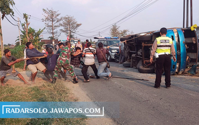 GOTONG ROYONG: Warga bersama aparat menarik minibus yang terguling di Jalan Bangak-Simo tepatnya di Desa Trayu, Banyudono Rabu (24/8) pukul 14.30. (RAGIL LISTIYO/RADAR SOLO)