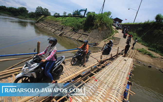 ANTREAN PANJANG: Para pengendara melintasi jembatan rakitan yang menghubungkan Kampung Beron, Kelurahan Sewu, Solo dengan Desa Gadingan, Mojolaban Sukoharjo, kemarin. (ARIEF BUDIMAN/RADAR SOLO)
