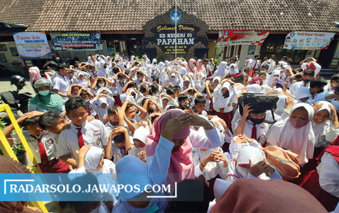 HANYA SIMULASI: Siswa beserta guru SDN 1 Papahan Tasikmadu berkumpul di halaman sekolah dengan melindungi kepala dengan tas saat mengikuti simulasi gempa bumi, Rabu (14/9). (RUDI HARTONO/RADAR SOLO)