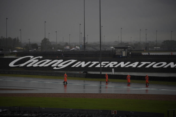 People sweep water off the track as practice and qualifying sessions are delayed due to adverse weather conditions during the Thailand MotoGP at Buriram International Circuit in Buriram on October 5, 2019. (Photo by Lillian SUWANRUMPHA / AFP)