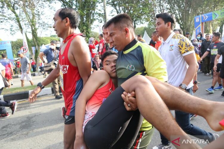 Seorang peserta saat dibopong menuju ambulans untuk mendapatkan pertolongan di garis finis Balikpapan 10 K, Minggu (4/9). (Novi Abdi/Antara)
