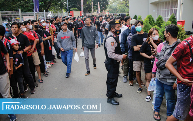TERTIB: Anggota Polresta Surakarta berinteraksi dengan penonton sepak bola yang antre untuk masuk ke Stadion Manahan belum lama ini. (M. IHSAN/RADAR SOLO)
