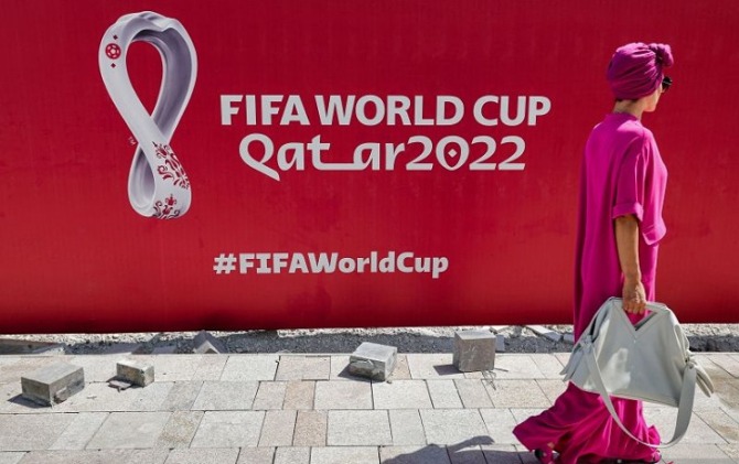 Seorang wanita berjalan di depan baliho besar logo Piala Dunia FIFA 2022 di West Bay Doha, Qatar pada 13 Oktober 2022 (ANTARA/AFP/GIUSEPPE CACACE)