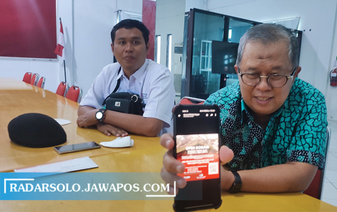TEROBOSAN: Ketua PMI Kabupaten Sragen Ismail Joko Sutresno (kanan) menunjukkan cara donasi lewat QRIS. (AHMAD KHAIRUDIN/RADAR SOLO)