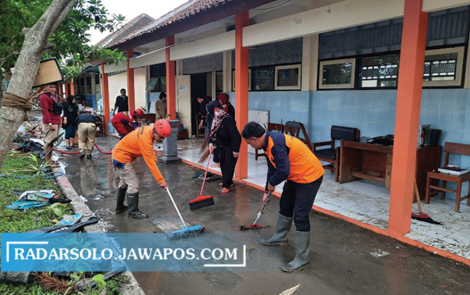Petugas gabungan BPBD Sukoharjo bersama siswa, para guru, dan karyawan SMAN 1 Weru membersihkan lingkungan pasca diterjang banjir, kemarin (21/11). (IWAN KAWUL/RADAR SOLO)