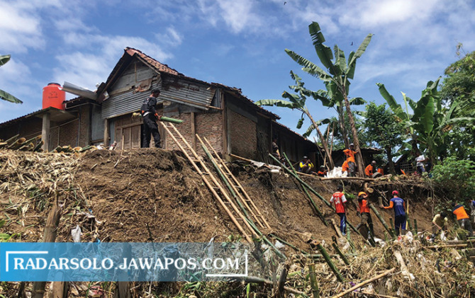 ANTISIPAI: Relawan gabungan dan warga menahan longsoran tanggul Sungai Siluwur dengan bambu, tepat di bawah rumah warga di Desa Karangwuni, Weru, Senin (28/11). (IWAN KAWUL/RADAR SOLO)