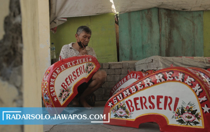 TETAP BERTAHAN: Sri Sunarto sedang melukis bagian bodi becak di rumahnya Banjarsari, Minggu (18/12). (A. CHRISTIAN/RADAR SOLO)