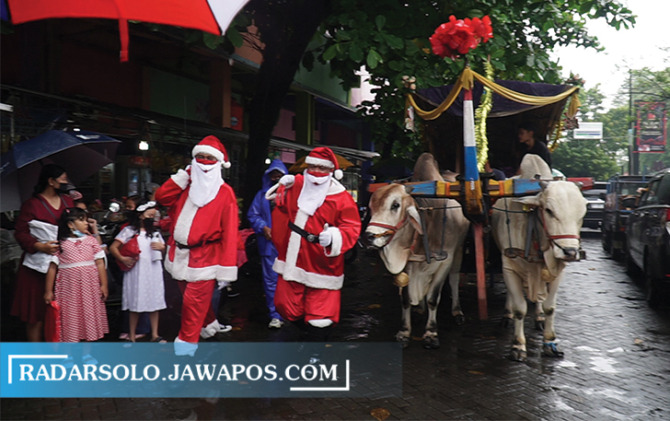 RAYAKAN NATAL: Sejumlah Sinterklas membagikan kado Natal di Pasar Boyolali Kota, dengan menaiki gerobak sapi, Minggu (25/12). Selain pasar, juga bagikan kado ke panti asuhan. (RAGIL LISTIYO/RADAR SOLO)