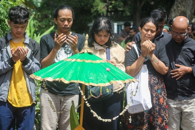 Anak Wiji Thukul, Fajar Merah (dua dari kiri) dan Fitri Nganti Wani (dua dari kanan) berdoa di pusara Sipon, sang ibu yang meninggal dunia, Kamis (5/1/2023) dan dimakamkan Jumat (6/1/2023). (M IHSAN/RADAR SOLO)