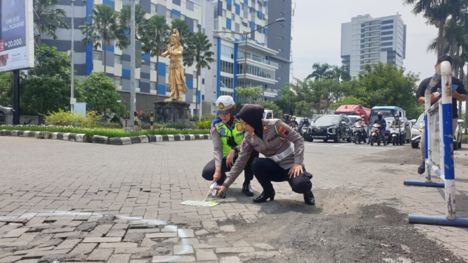 DISEMPROT CAT: Dua polwan dari Satlantas Polres Sukoharjo menandai jalan yang rusak, tepatnya di simpang empat Patung Pandawa Solo Baru, Kecamatan Grogol, Rabu (4/1/2023). (IWAN KAWUL/RADAR SOLO)