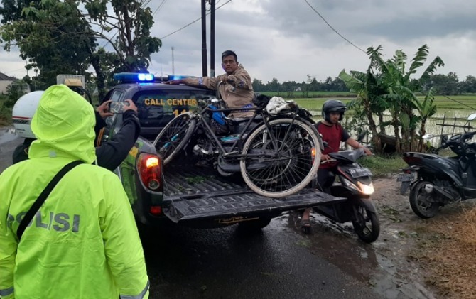 Polisi mengevakuasi sepeda milik buruh tani yang tertimpa pohon saat hujan deras disertai angin kencang di Mojolaban, Sabtu (21/1). (IWAN K/RADAR SOLO)
