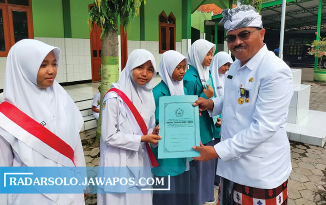 HUMBLE: Kepala MTsN 2 Sragen M. Aris Suparlan memberikan memberikan penghargaan ke siswa di momen Hari Amal Bhakti ke-77 Kemenag 2023, Selasa (3/1/2023). (AHMAD KHAIRUDIN/RADAR SOLO)