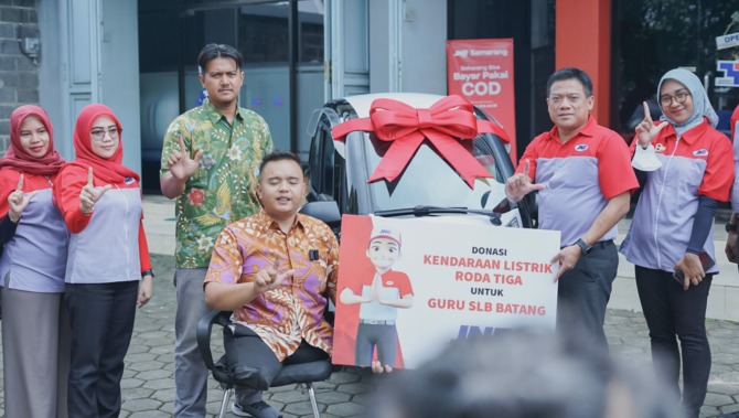 Hikmat (tengah) seorang guru difabel yang mendapatkan bantuan kendaraan listrik dari JNE. (ISTIMEWA)