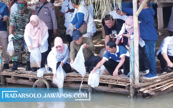 SIMBOLIS: Bupati Karanganyar Juliyatmono tebar benih nila di Embung Setumpeng, Mojogedang, Jumat (13/1/2023). (RUDI HARTONO/RADAR SOLO)