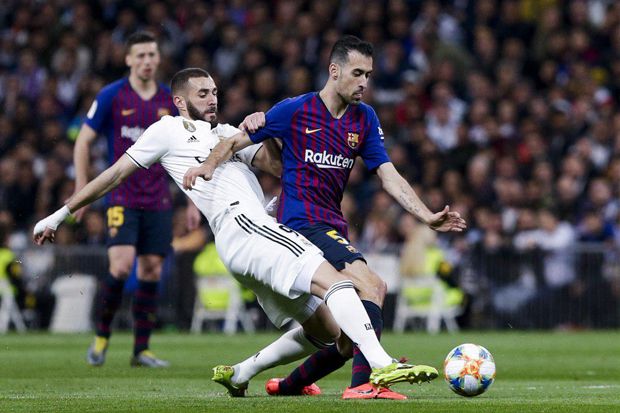 KETAT: Penyerang Real Madrid Karim Benzema tengah berebut bola dengan pemain tengah Barcelona Sergio Busquets di ajang el clasico, tahun lalu. Final Supercopa Spanyol kali ini bakal menjadi pertandingan yang ketat. (Twitter @realmadrid)