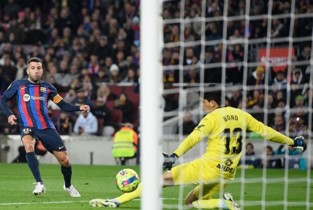 Bek Barcelona Jordi Alba (kiri) menendang bola untuk mencetak gol pada pertandingan Liga Spanyol melawan Sevilla di Stadion Camp Nou, Barcelona, Senin (6/2) dini hari WIB. (Josep Lago/AFP/Antara)