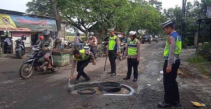ANTISIPASI: Satlantas Polres Sukoharjo memberikan tanda di titik-titik lubang jalur Sukoharjo menuju Pasar Bekonang menggunakan cat semprot warna putih, Selasa (28/2/2023). (IWAN KAWUL/RADAR SOLO)