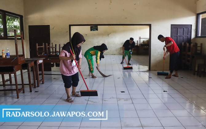 Sejumlah guru SDN Mijipinilihan dan pihak terkait melakukan kegiatan gotong royong bersih-bersih pasca banjir yang menggenangi kawasan Joyotakan, Minggu (19/2/2023). (M. IHSAN/RADAR SOLO)