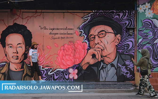 INSTAGRAMABLE: Seorang wisatawan tengah berfoto dengan background mural Wiji Thukul dan Prof. Dr. Sapardi Djoko Damono di Koridor Gatsu, belum lama ini.  (ARIEF BUDIMAN/RADAR SOLO)