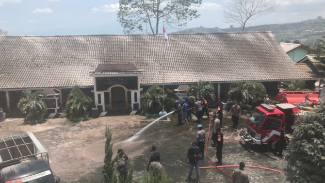 Petugas Damkar Boyolali dibantu relawan dan elemen lainnya menyemprotkan air di halaman SDN2 Tlogolele, Desa Tlogolele, Kecamatan Selo, Kabupaten Boyolali untuk membersihkan abu vulkanis, Senin (13/3/2023). (ARIEF BUDIMAN/RADAR SOLO)