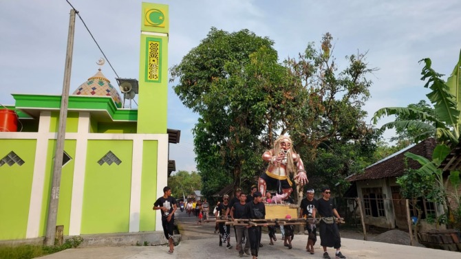 Arak-arakan ogoh-ogoh dalam upacara Mecaru Hari Raya Nyepi melintasi Masjid Al Fatah di Dusun Ngledok, Desa Gumukrejo, Kecamatan Teras, Kabupaten Boyolali, Selasa (21/3). (RAGIL LISTIYO/RADAR SOLO).
