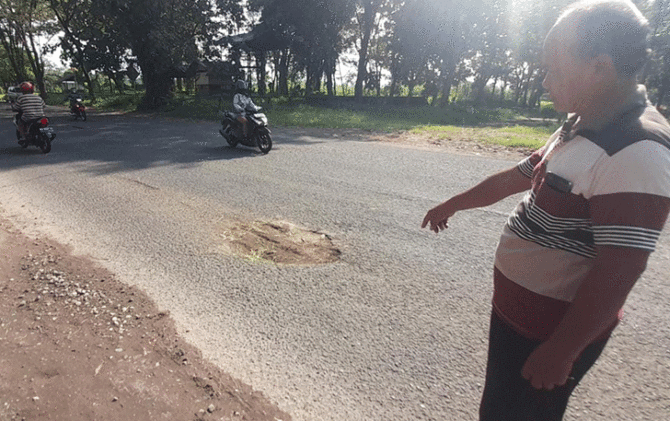 Warga tunjukkan lubang jalan di jalur Tasikmadu-Papahan, tepatnya di cafe PG Tasikmadu, yang memakan korban meninggal, Kamis (9/3). (RUDI H/RADAR SOLO)