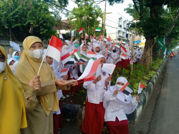 HARUS DITINGKATKAN: Guru dan siswa SD negeri di Kota Solo mengibarkan bendera di tepi Jalan Slamet Riyadi, sambut tamu negara. (SEPTIAN REVFINDA/RADAR SOLO)