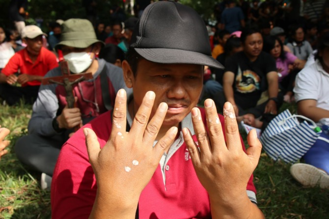 Seorang umat menunjukkan tangannya usai ditetesi lilin saat Jalan Salib di Gunung Gandul Jumat (7/4/2023). (IWAN ADI LUHUNG/RADAR SOLO)