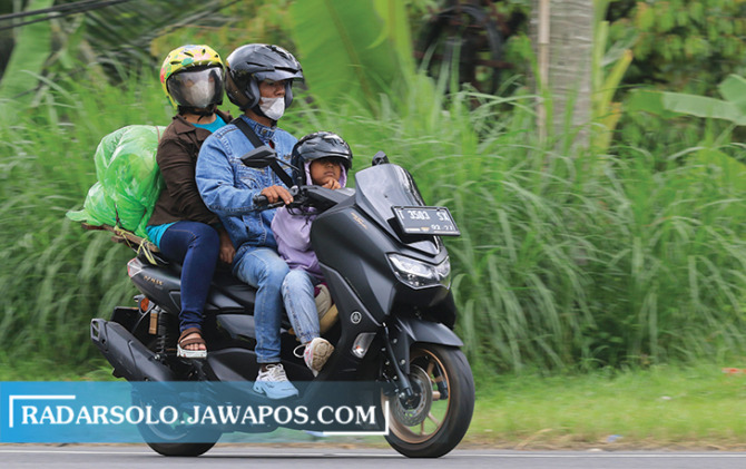 MEMBAHAYAKAN: Keluarga yang tengah melintasi jalan Boyolali-Semarang dengan membawa barang yang cukup banyak, kemarin. (ARIEF BUDIMAN/RADAR SOLO)