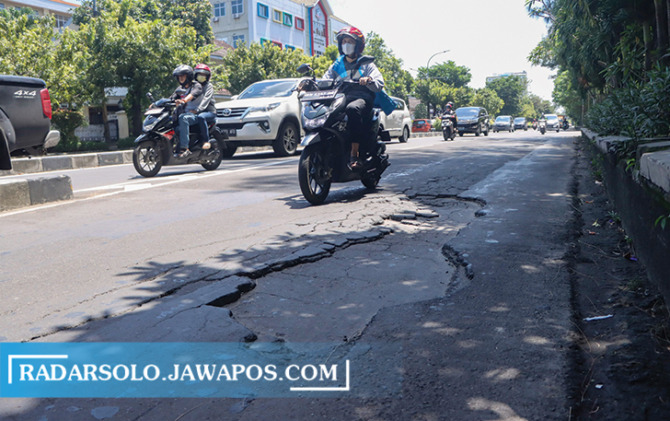 HATI-HATI: Pengendara melintas di Jalan Adi Sucipto yang terlihat ada beberapa kerusakan pada aspal di ruas jalan tersebut. (M. IHSAN/RADAR SOLO)