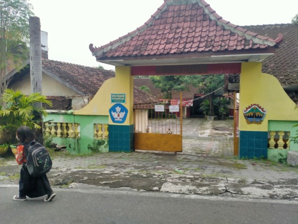 TAHUN TERAKHIR: Siswa berjalan pulang sekolah di depan gerbang SDN Tugu Jebres No. 120 Surakarta, yang tahun ajaran baru ini tidak lagi menerima peserta didik baru. (SEPTIAN REFVINDA/RADAR SOLO)