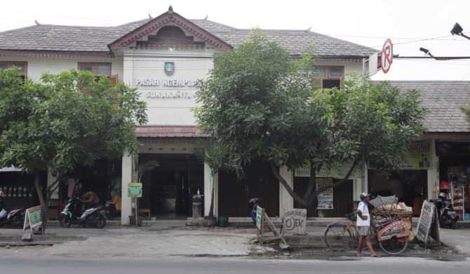 BERUBAH KONSEP: Tukang becak berdiri di depan bangunan Pasar Ngemplak. Pasar ini direncanakan akan berubah wajah jadi pusat oleh-oleh dan penjualan cinderamata. (M. IHSAN/RADAR SOLO)