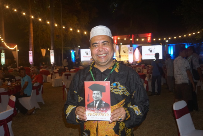 LAUNCHING: Paiman tunjukkan bukunya berjudul Tukang Sapu Jadi Profesor di PG Gondang Baru Klaten, Sabtu malam (27/5/2023). (ANGGA PURENDA/RADAR SOLO)