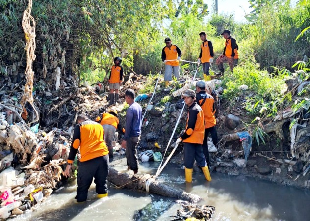SERING MELUAP: Relawan membersihkan sampah yang memenuhi sungai di bawah jembatan Dalon, Desa Sroyo, Jaten, Minggu (28/5/2023). (RUDI HARTONO/RADAR SOLO)