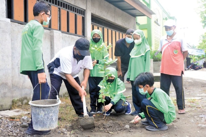 JAGA LINGKUNGAN: Siswa dan guru MIN 2 Sukoharjo melakukan penghijauan di lingkungan madrasah setempat. (AHMAD KHAIRUDIN/RADAR SOLO)