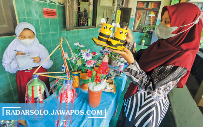 DIASAH KETERAMPILANNYA: Guru dan siswa dalam pameran daur ulang sampah, bagian dari Implementasi Kurikulum merdeka di salah satu SD negeri di Kota Solo, belum lama ini. (M. IHSAN/RADAR SOLO)